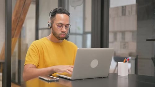 Smiling Young Adult Using Laptop With Headset