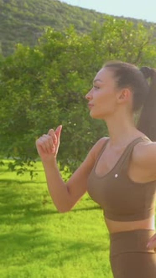 Fit young woman jogging outdoors in a park during golden hour, enjoying a healthy lifestyle