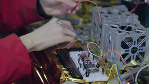 Der Elektriker verdreht die Kabel des auf einem 3D-Drucker gedruckten Ersatzteils für den Satelliten mit der Hand