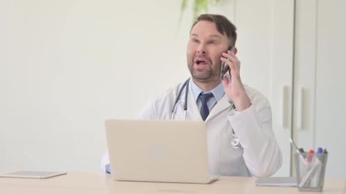 Doctor in Lab Coat Talking on Phone at Desk