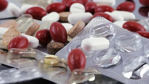 Fallende Tabletten und Pillen auf einer Metalloberfläche und pharmazeutische Blisterpackung. Zeitlupe.