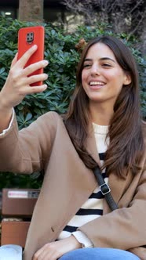 Vertical videoYoung Influencer Woman Doing a Live Show with a Mobile Phone in a City