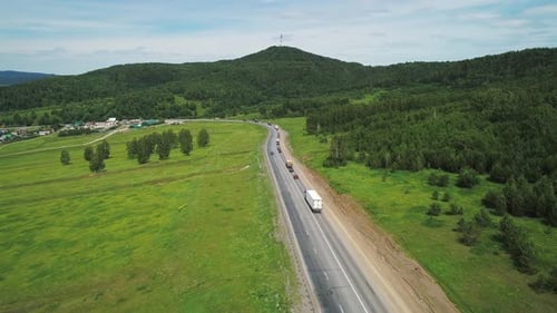 Aerial View of an Intercity Highway with Traffic Going Through Green Meadows and Trees on a Sunny
