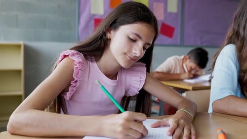 Young Student Girl Writing in Notebook While Studying at Primary School