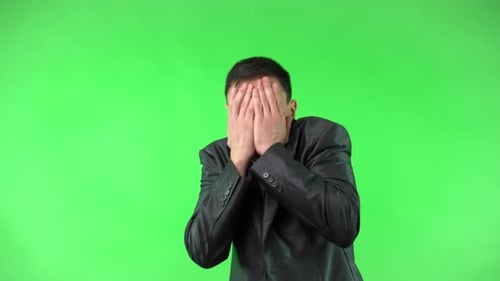 Verängstigter Kerl, der sein Gesicht vor Chroma Key verdeckt