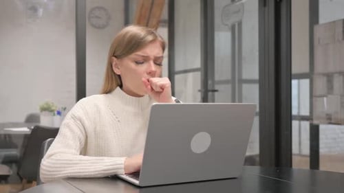 Young Woman Coughing While Working on Laptop