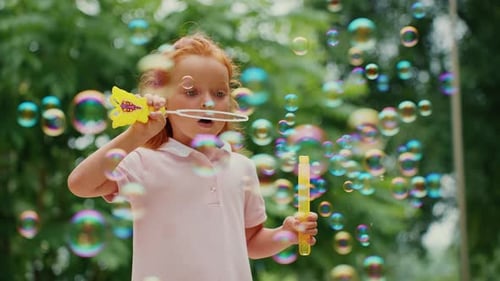 Child Blowing Bubbles in a Sunny Garden During Summer Afternoon