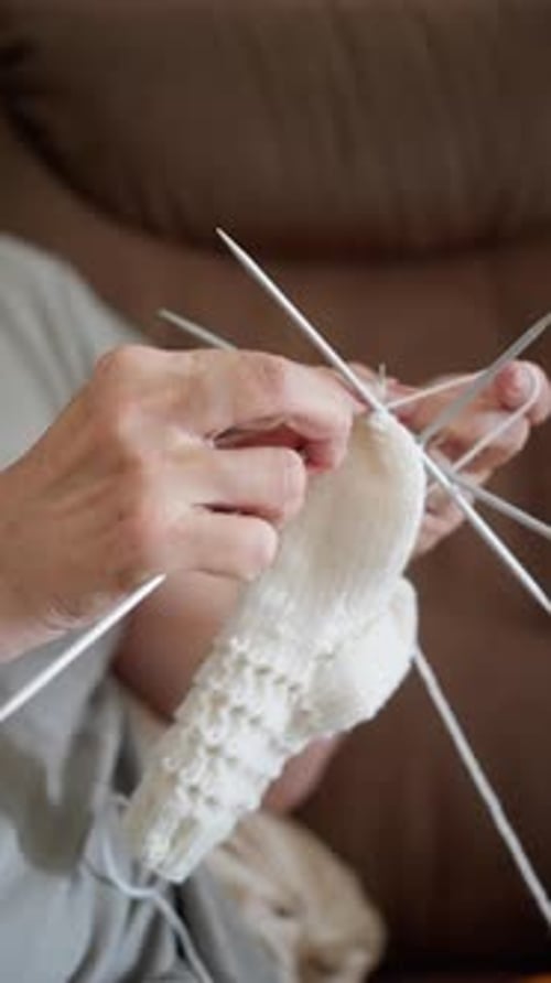 Woman Knits with Knitting Needles and White Yarn