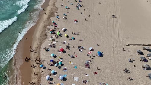 Aerial View of a Busy Beach with Colorful Umbrellas and Sunbathers Enjoying Their Day