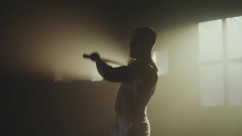 Man Exercising with Sledgehammer and Tire Indoors