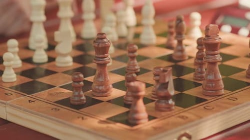 Male Hand Making Move with Chess Piece on Board Close Up