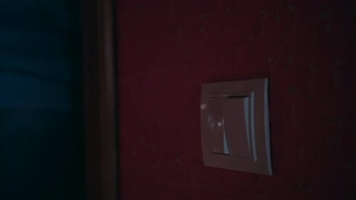 Uma mão ligando e desligando um interruptor de luz em uma casa