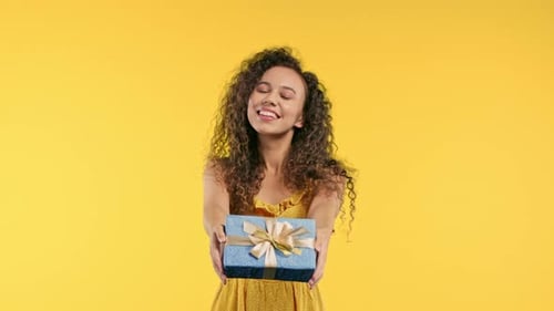 Woman Presents Gift Box on Yellow Background