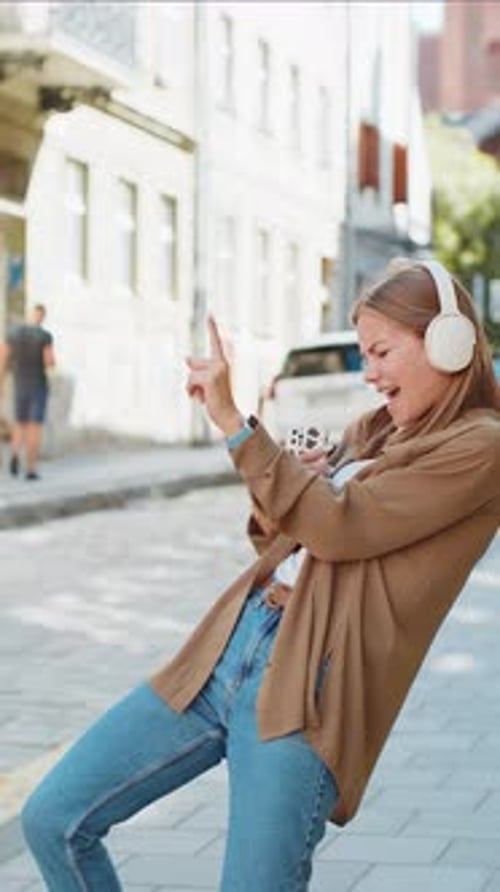 Happy Woman in Wireless Headphones Dancing Listening Favorite Energetic Music Singing on Street