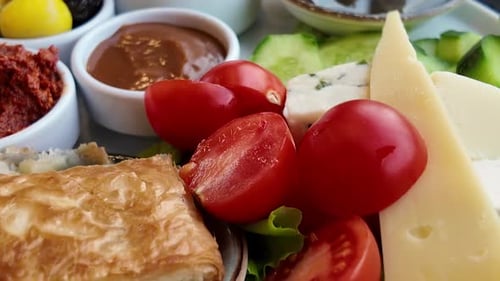 Delicious Breakfast Plate Featuring Cheese, Tomatoes, and Pastries
