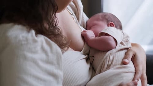 Mother Breastfeeding Newborn Infant in Gentle Daylight