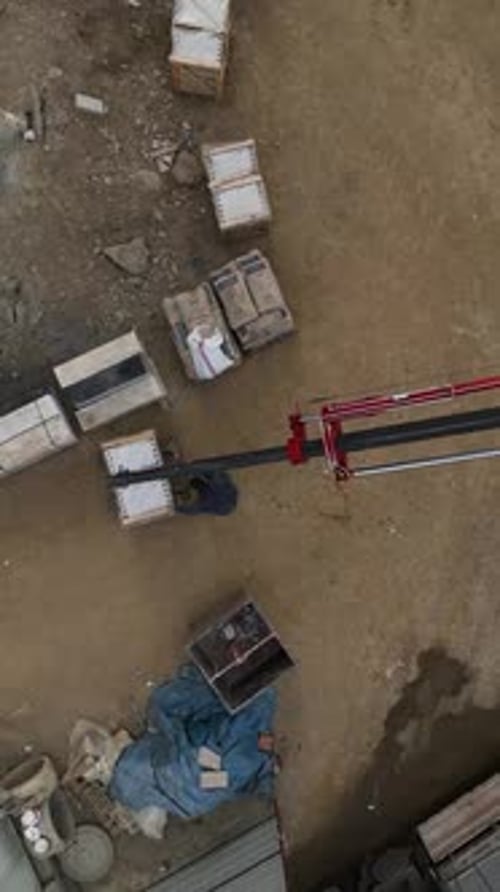 Vertical Video Aerial Wonder Construction Site with Crane Unloading Cargo and Builders in Progress