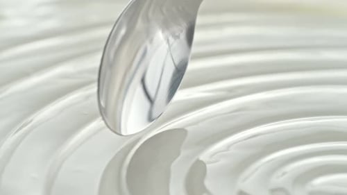 Plain Greek Yogurt Scooped with Silver Spoon from a White Bowl in Macro and Slow Motion
