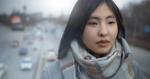 Portrait of a Sad Asian Woman Standing in the Background of the City and the Road
