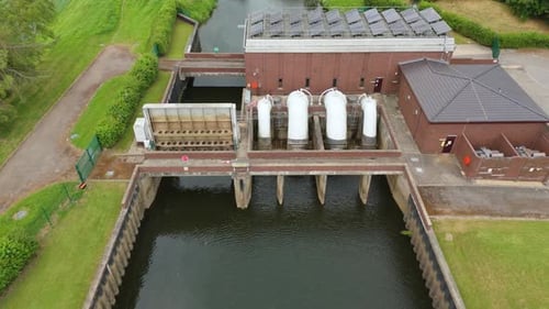 Scenic Aerial Shot of Hydroelectric Facility and Pumping Station Alongside Rural Riverbanks in Engla
