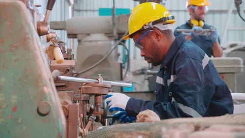 Young black engineer man operating lathe machine for preparing production at factory industrial.
