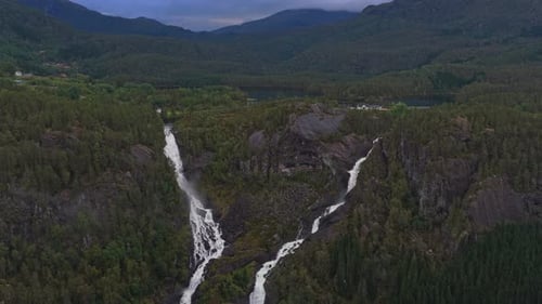 Waterfall tumbling through green highlands in Norway aerial view