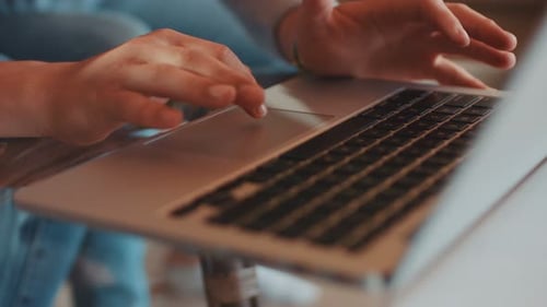 Hands using laptop trackpad for technology at home