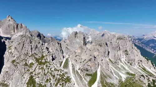 Aerial drone view of the dramatic Dolomites mountain range with steep grey cliffs and alpine valleys