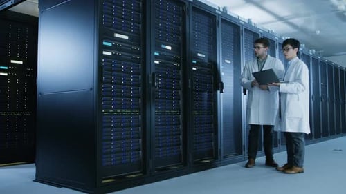 In the Data Center: Two IT Specialists Wearing White Lab Coats, Have Discussion about Working of Se
