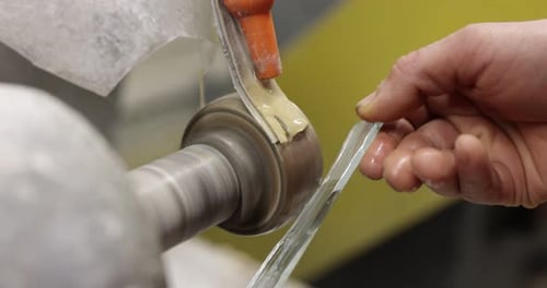 Worker grinding piece of glass in workshop, closeup