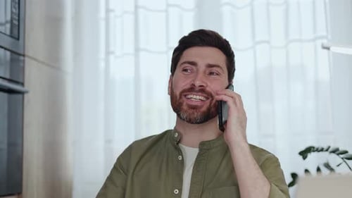 Man Talking on Phone and Drinking Coffee Indoors