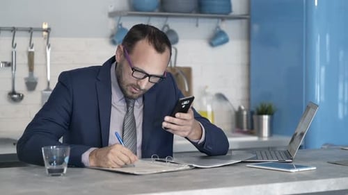 Man in suit using phone, working in kitchen