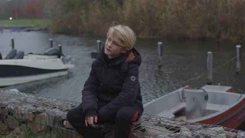 Wide view of young boy reminiscing next to river