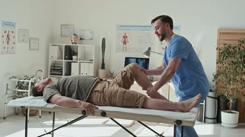 Physiotherapist Doing Stretching Exercises on Legs of Patient
