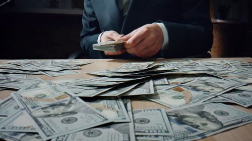 Unknown rich man counting heap us dollars in elegant suit at office desk