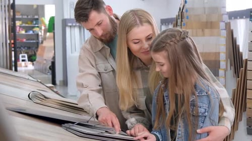 A Young Family in a Hardware Store Chooses a Wooden Laminate Surface for Home Renovation