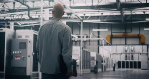 IT Engineer Walking Through Server Room with Laptop