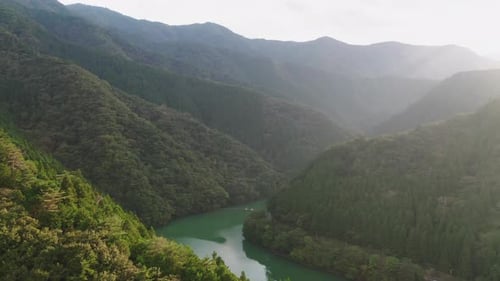 River Between Forested Mountain At Sunrise In Okutama, Japan. - aerial