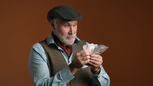 Senior Man Counting Money Orange Background