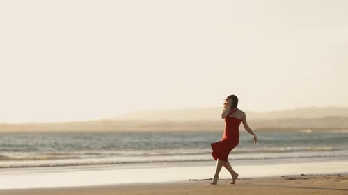 Woman Dancing Freely on Sandy Beach at Sunset