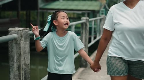 Mother and Daughter Walking Together Holding Hands in a Park