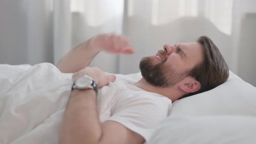 Side View of Young Adult Man with Headache in Bed