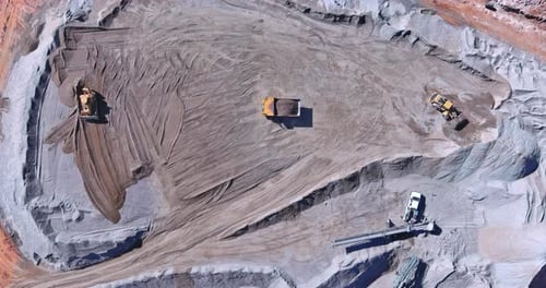 Excavation Activity in a Large Construction Site During Daytime Near a Rocky Terrain