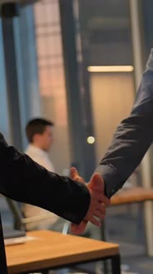 Vertical of Two Entrepreneur Shaking Hands Inside of Modern Business Office with Huge Windows