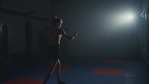Boxtraining in einem schwach beleuchteten Fitnessstudio mit Schwerpunkt Technik und Schattenbewegung
