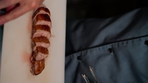 Professional restaurant kitchen chef cuts delicious roasted duck breast with a knife asian cuisine