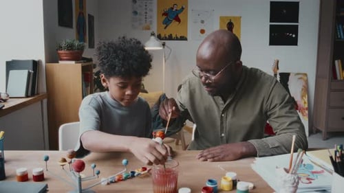 Man and Child Painting a Solar System Model