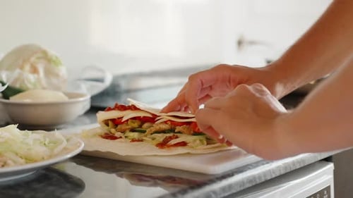 Cooking, I wrap shawarma. Close-up in motion. Black stone countertop. White cutting board.