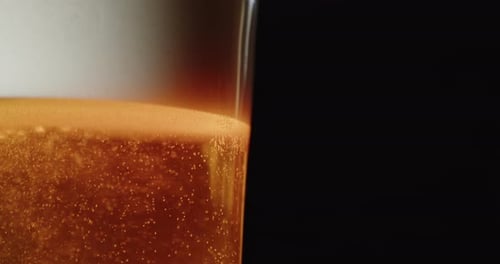 Beer glass on black background with space for slogan or headline. Beer foam and bubbles. Packshot st