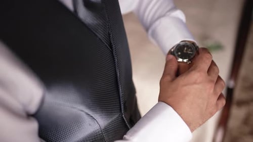 Close up of groom adjusting wristwatch before wedding ceremony